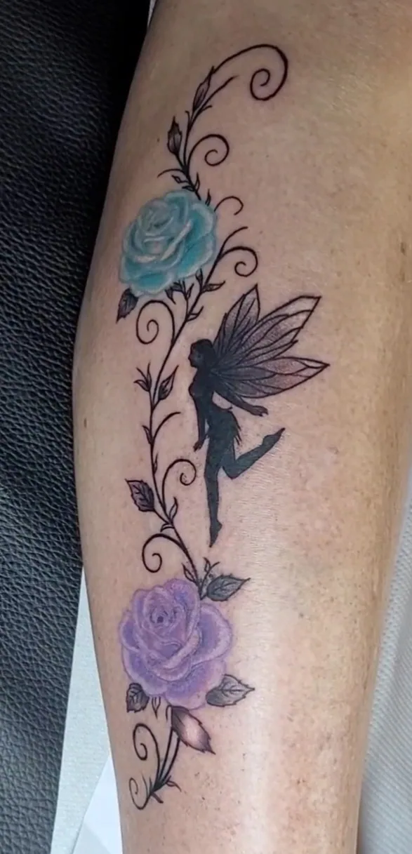 Tatouage couleur d'une fée et de roses bleutées sur le mollet, réalisé par Jean-Marie Joullié au salon JMJ Tattoo proche de Marseillan