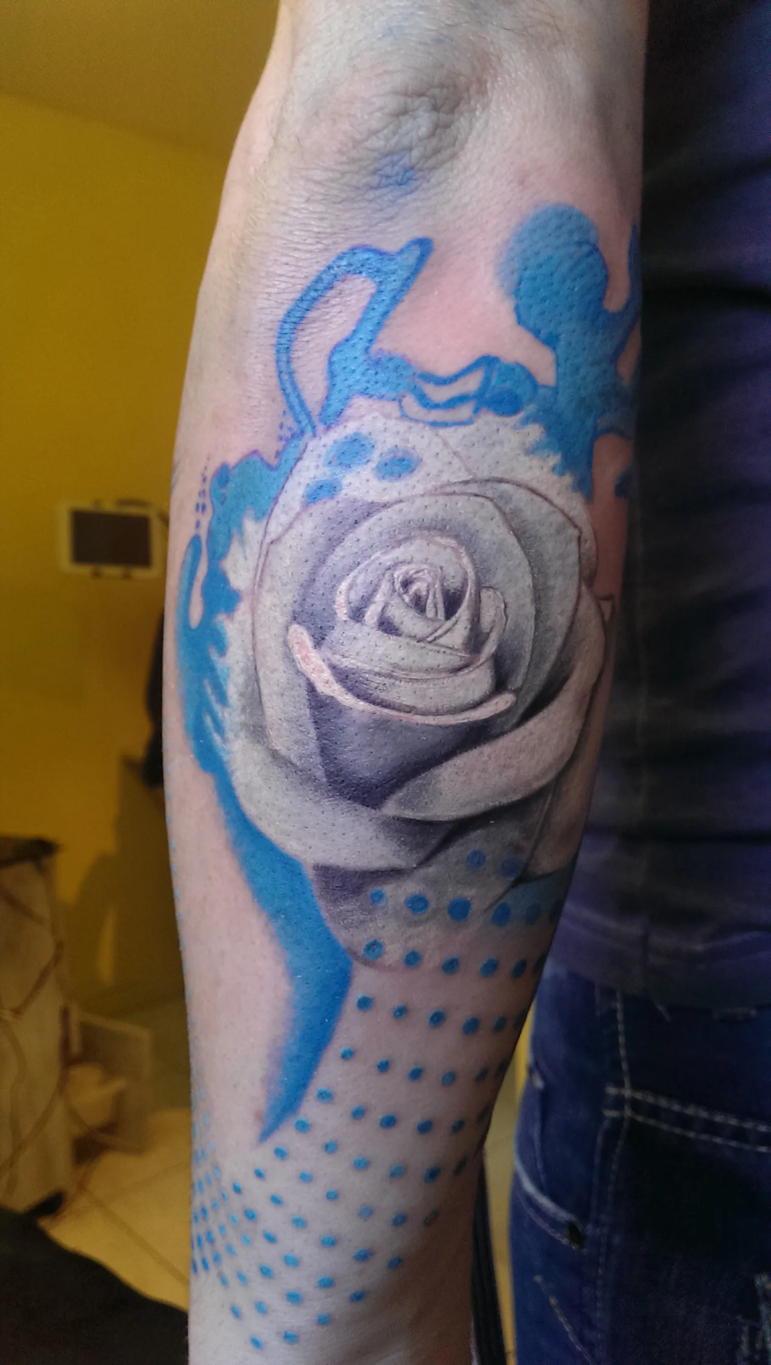 Tatouage couleur d'une rose en style aquarelle avec éclaboussures sur l'avant-bras, réalisé par Jean-Marie Joullié au salon JMJ Tattoo proche de Pézenas
