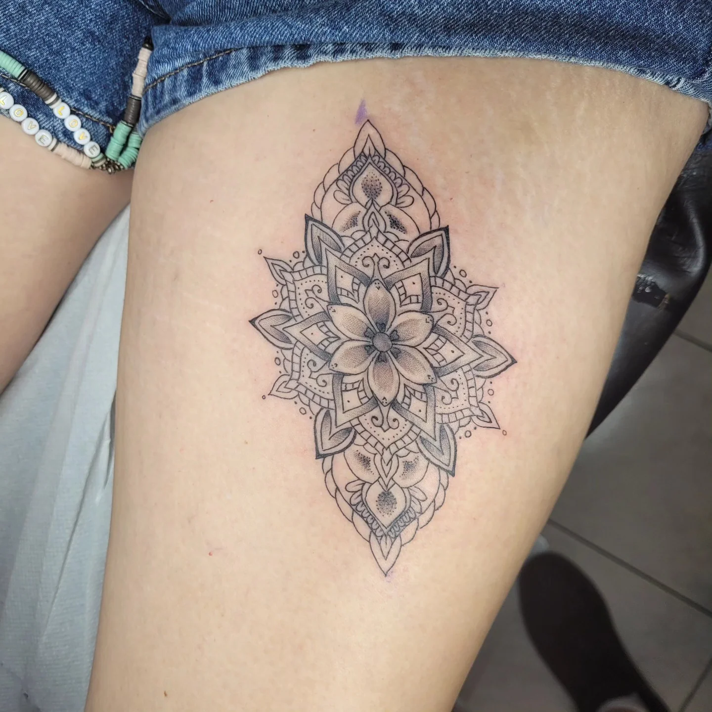 Tatouage fine line d'un mandala floral géométrique sur la cuisse, réalisé par Jean-Marie Joullié au salon JMJ Tattoo proche de Pézenas