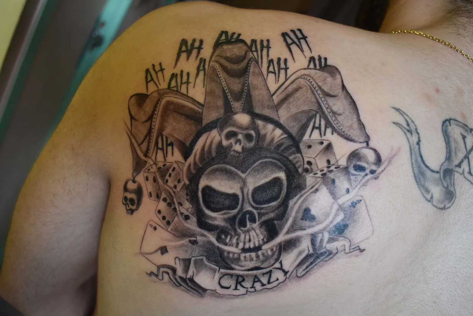 Tatouage noir et gris d'un crâne de bouffon avec cartes à jouer et dés sur le dos, réalisé par Jean-Marie Joullié au salon JMJ Tattoo proche de Villeneuve-lès-Béziers