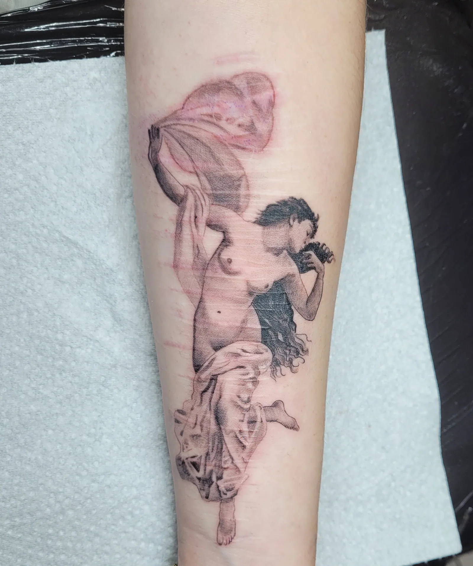 Tatouage réaliste noir et gris d'une femme drapée de style classique sur l'avant-bras, réalisé par Jean-Marie Joullié au salon JMJ Tattoo à Béziers et Sérignan